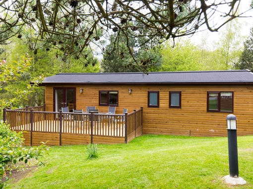 Exterior of lodge with decking to the side with outdoor furniture
